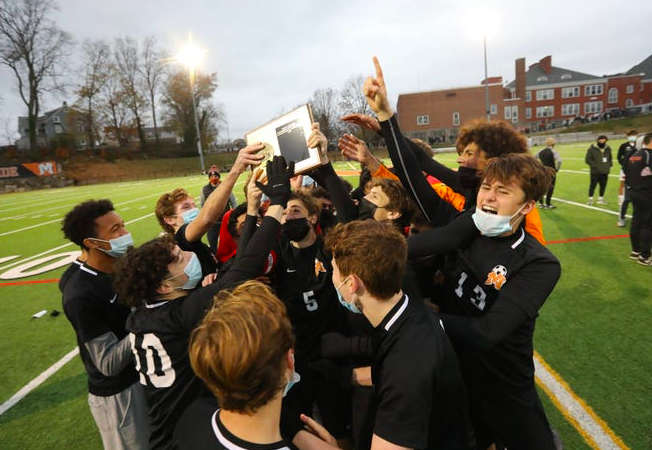 The Mamaroneck boys varsity soccer team raises the championship plaque as a unit after beating White Plains.