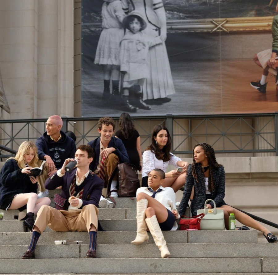 Main characters from the reboot pose in their fashionable outfits on outdoor steps.